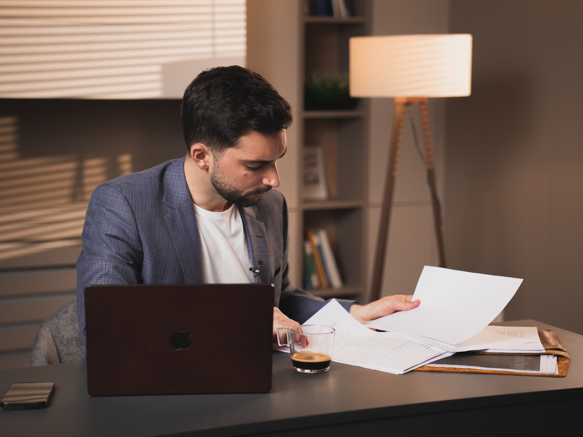Branko Džakula at a desk reviewing papers with a laptop and espresso.