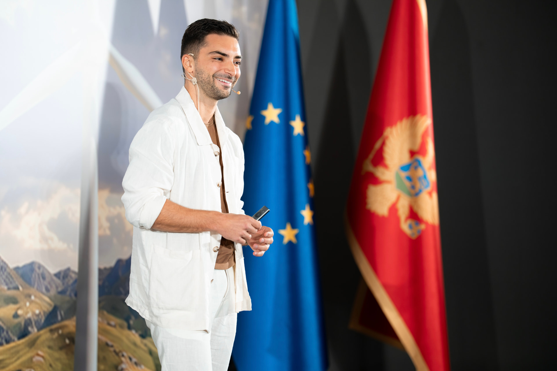 Branko Džakula speaking on stage in front of the European Union and Montenegrin flags.